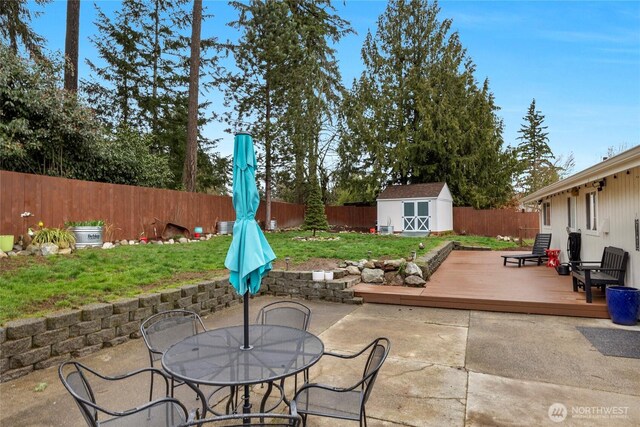 view of patio featuring a storage shed, a fenced backyard, an outbuilding, and a wooden deck