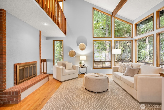 living area featuring a healthy amount of sunlight, a fireplace, high vaulted ceiling, and wood finished floors