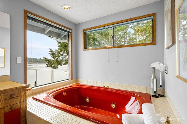 bathroom with a healthy amount of sunlight, a whirlpool tub, and a textured ceiling