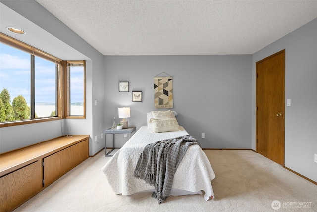 bedroom featuring baseboards, light carpet, and a textured ceiling