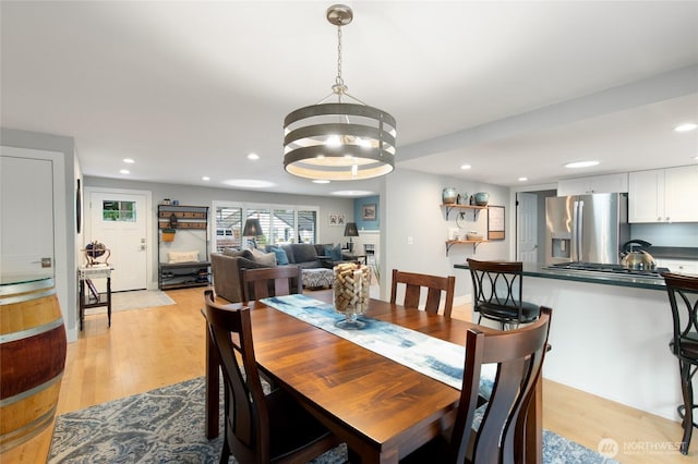 dining area with recessed lighting, light wood-style flooring, and an inviting chandelier