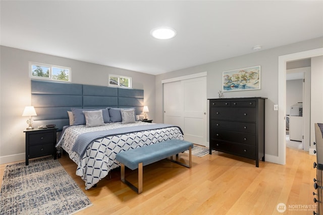 bedroom with light wood finished floors, baseboards, and a closet