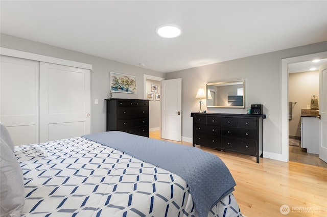 bedroom with baseboards, light wood-type flooring, and a closet