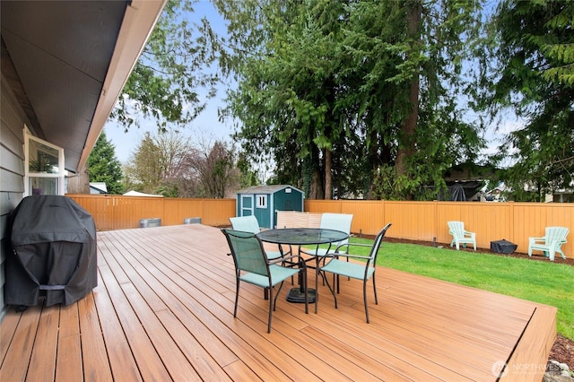 wooden terrace featuring a storage unit, outdoor dining area, a fenced backyard, and an outdoor structure