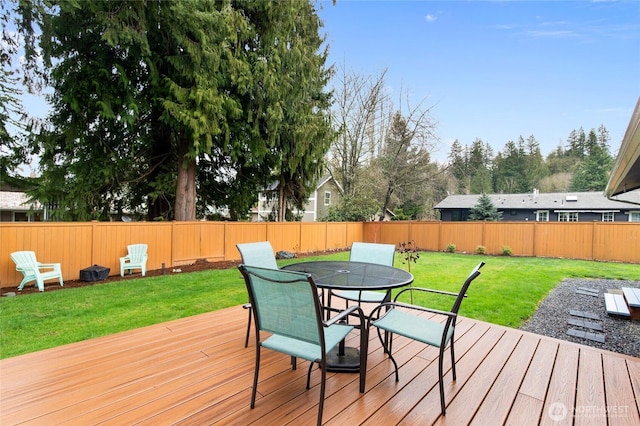 wooden terrace with outdoor dining space, a lawn, and a fenced backyard