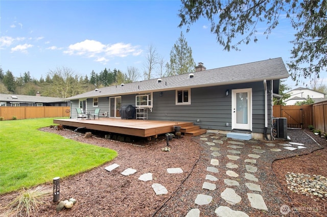 back of property with central air condition unit, a yard, a fenced backyard, and a chimney