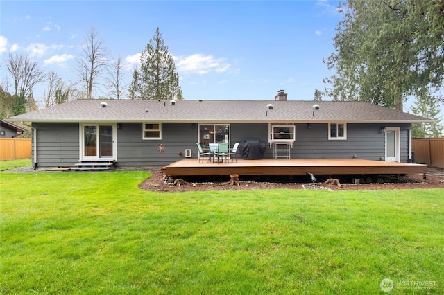 back of property with a deck, entry steps, fence, a yard, and a chimney