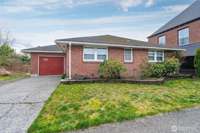 view of front of house featuring brick siding, a garage, aphalt driveway, and a front lawn