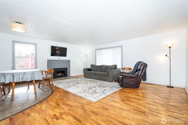 living area with baseboards, a fireplace with flush hearth, and wood finished floors