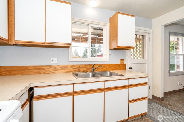 kitchen featuring white cabinetry, light countertops, baseboards, and a sink