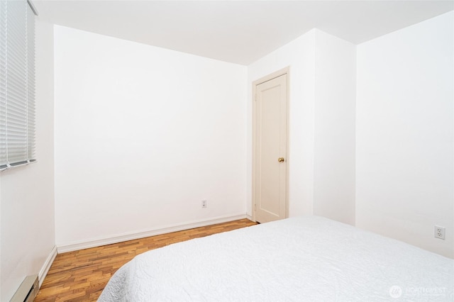 bedroom featuring baseboard heating, baseboards, and wood finished floors