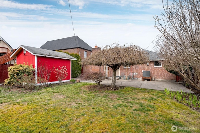 view of yard with a storage shed, an outbuilding, and a patio area