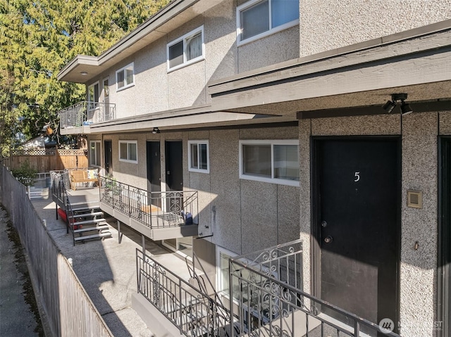 exterior space featuring a balcony, fence, and stucco siding