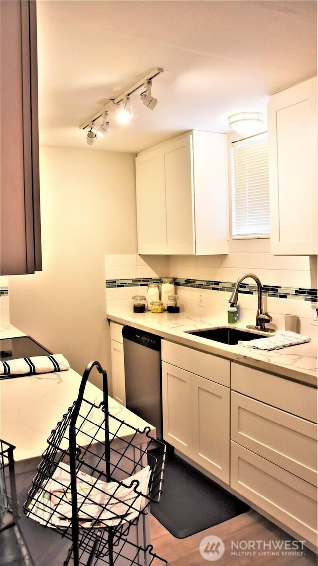 kitchen with dishwasher, tasteful backsplash, white cabinetry, and a sink