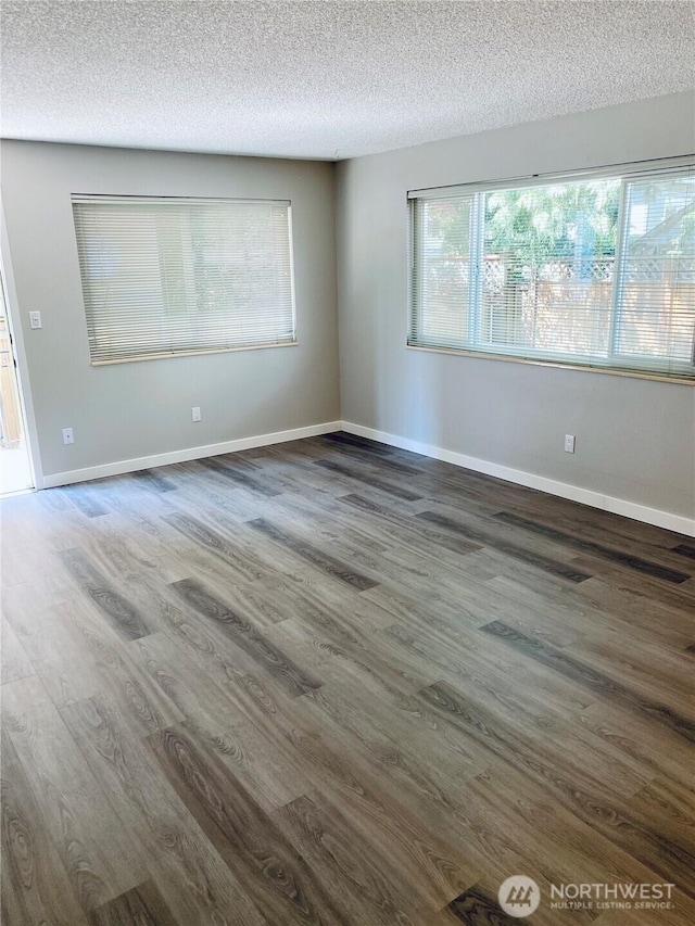 empty room featuring wood finished floors, baseboards, and a textured ceiling