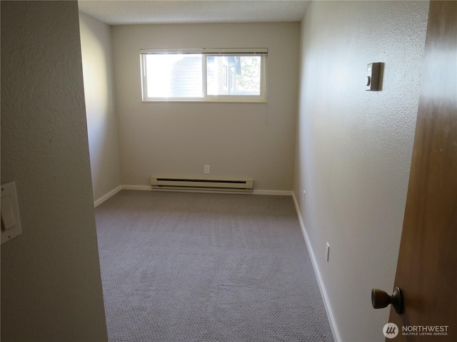 carpeted empty room featuring baseboard heating and baseboards