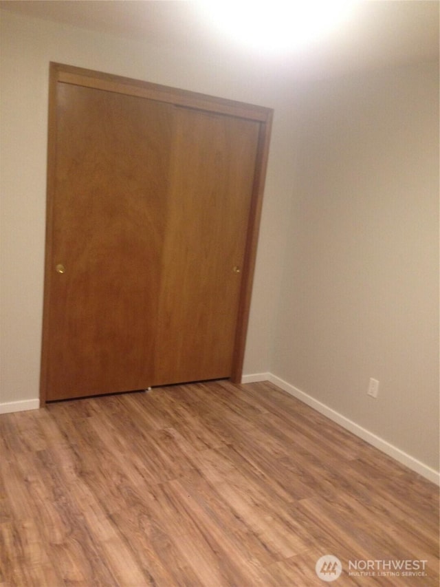 unfurnished bedroom with a closet, baseboards, and light wood-style floors