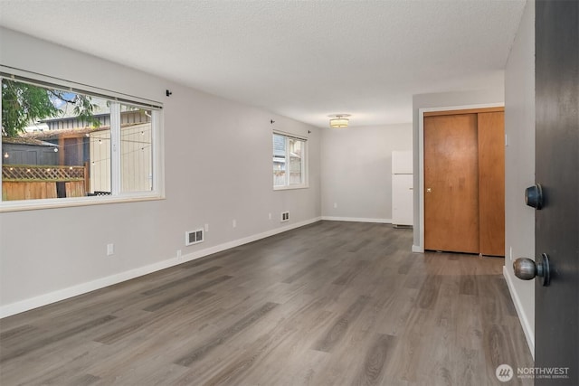 empty room featuring wood finished floors, a textured ceiling, and baseboards