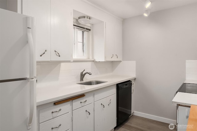 kitchen with freestanding refrigerator, a sink, dishwasher, white cabinets, and light countertops