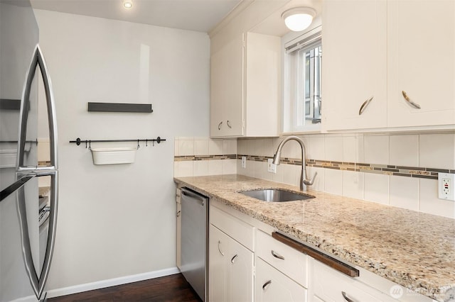kitchen featuring a sink, appliances with stainless steel finishes, backsplash, baseboards, and white cabinetry