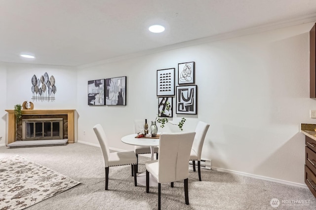 carpeted dining room with crown molding, baseboards, recessed lighting, a glass covered fireplace, and a baseboard radiator