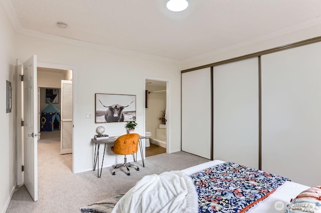 bedroom with a closet, light colored carpet, connected bathroom, and crown molding