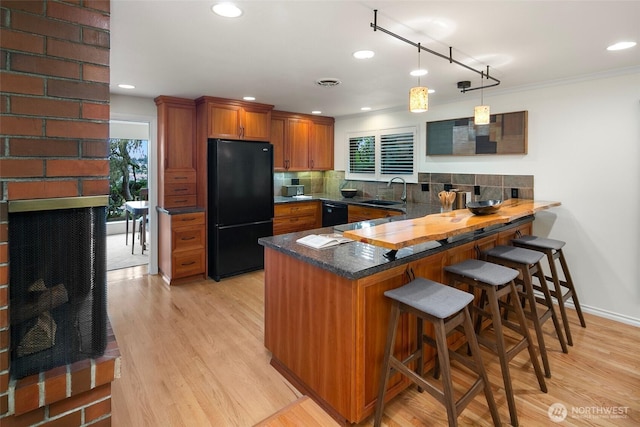 kitchen featuring black appliances, tasteful backsplash, a peninsula, and brown cabinets