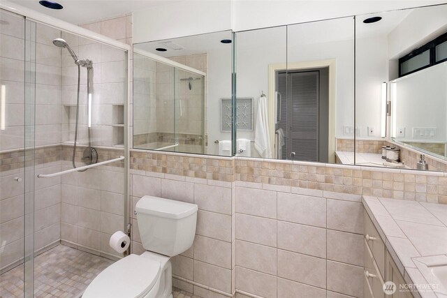 full bathroom featuring vanity, a shower stall, and toilet