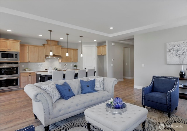 living area featuring light wood-style flooring, recessed lighting, and baseboards