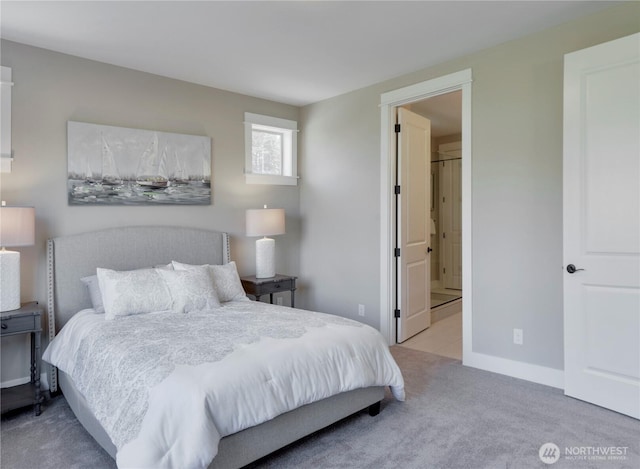 carpeted bedroom featuring ensuite bath and baseboards