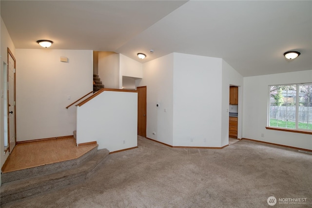 unfurnished living room featuring stairway, carpet flooring, baseboards, and vaulted ceiling