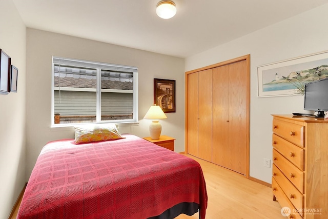 bedroom with a closet, light wood-style flooring, and baseboards