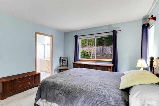 bedroom with light carpet and connected bathroom