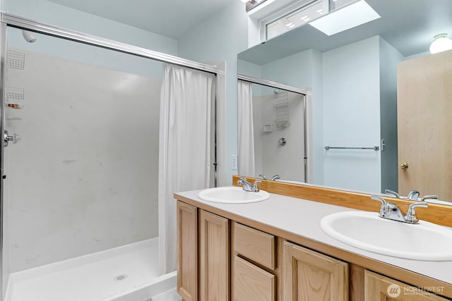 full bath with double vanity, a skylight, a stall shower, and a sink