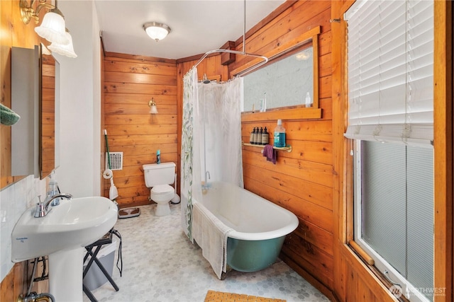 bathroom featuring toilet, a sink, curtained shower, wooden walls, and a bath