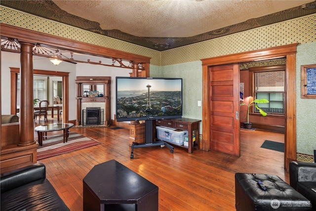 living area with hardwood / wood-style floors, a fireplace, ornate columns, and a textured ceiling