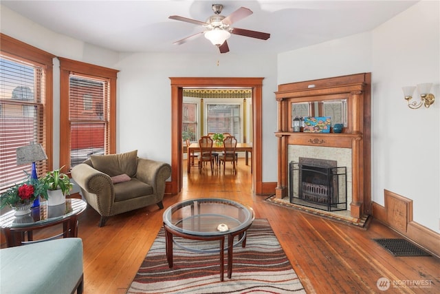 living room with visible vents, a fireplace, ceiling fan, and hardwood / wood-style flooring