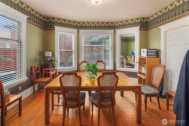 dining room featuring wallpapered walls, hardwood / wood-style flooring, and plenty of natural light