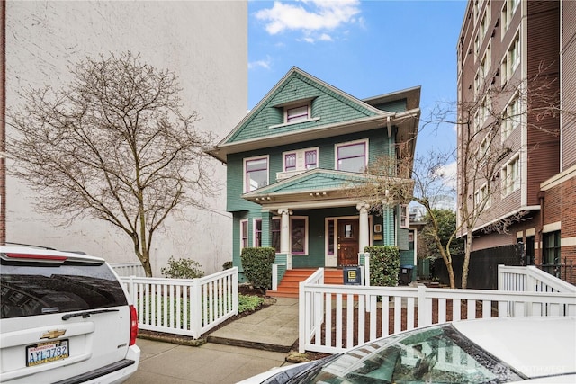 american foursquare style home featuring a fenced front yard and covered porch