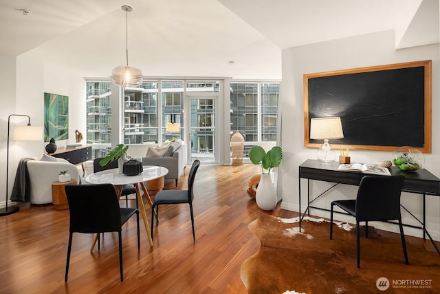 dining space with baseboards, lofted ceiling, and wood finished floors