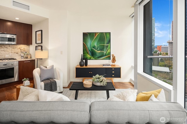 living area with visible vents, baseboards, and wood finished floors