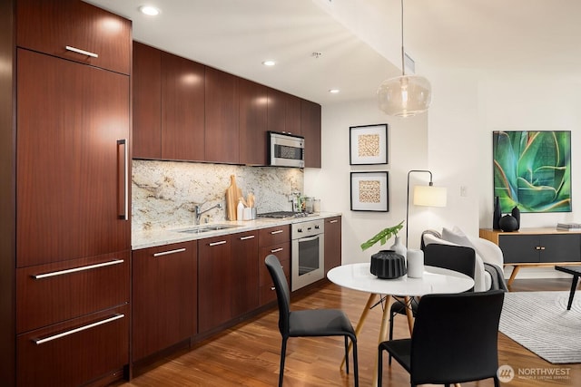 kitchen with modern cabinets, a sink, dark wood finished floors, stainless steel appliances, and decorative backsplash