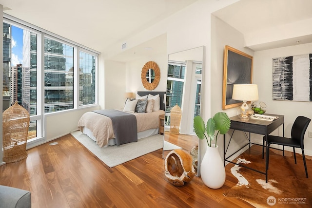 bedroom with visible vents, baseboards, and wood finished floors