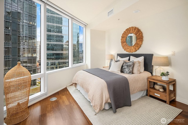 bedroom with wood finished floors, visible vents, and baseboards