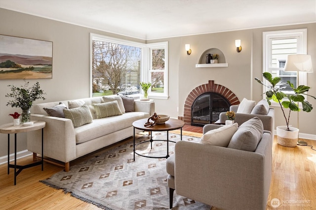 living room featuring a fireplace, baseboards, and wood finished floors