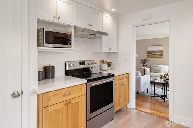 kitchen with light countertops, light wood-style floors, under cabinet range hood, and stainless steel appliances