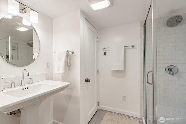 bathroom with a shower stall, baseboards, and a sink