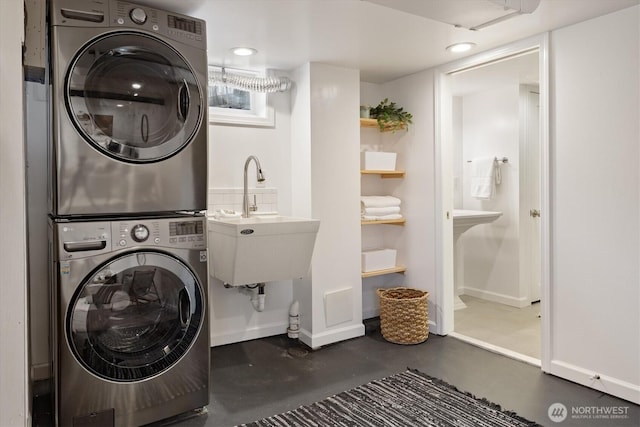 washroom featuring a sink, stacked washing maching and dryer, recessed lighting, baseboards, and laundry area