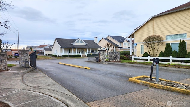 view of street with curbs, a residential view, and a gated entry