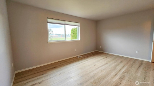 empty room with visible vents, baseboards, and wood finished floors